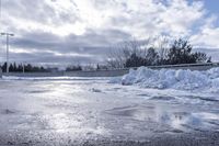 there is a large pile of snow next to a frozen road with a bridge behind it