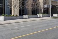 a city street has a building with large windows and white poles along it and a yellow line down the street