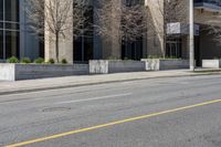 a city street has a building with large windows and white poles along it and a yellow line down the street