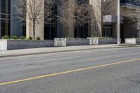 a city street has a building with large windows and white poles along it and a yellow line down the street