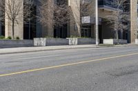 a city street has a building with large windows and white poles along it and a yellow line down the street