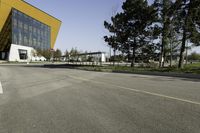 an empty street next to a very large building with many windows on the sides of it