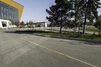 an empty street next to a very large building with many windows on the sides of it