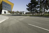 an empty street next to a very large building with many windows on the sides of it