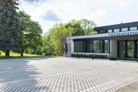 a commercial building sits on an empty lot surrounded by trees and grass in the sunlight