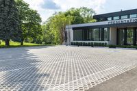 a commercial building sits on an empty lot surrounded by trees and grass in the sunlight