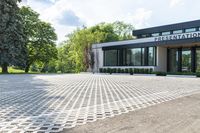 a commercial building sits on an empty lot surrounded by trees and grass in the sunlight