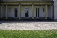 a bench outside of a big white building with pillars on both sides and glass windows