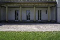 a bench outside of a big white building with pillars on both sides and glass windows