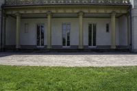 a bench outside of a big white building with pillars on both sides and glass windows