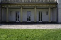 a bench outside of a big white building with pillars on both sides and glass windows