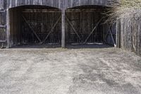 two wooden barn doors are open with hay covering the sides and bottom of it with the grass inside