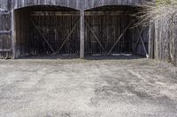 two wooden barn doors are open with hay covering the sides and bottom of it with the grass inside