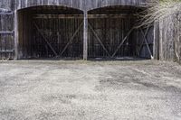 two wooden barn doors are open with hay covering the sides and bottom of it with the grass inside