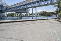 there is a concrete sidewalk and some bridge that spans the river's edge with a blue sky