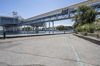 there is a concrete sidewalk and some bridge that spans the river's edge with a blue sky