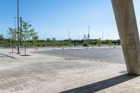 an empty parking lot under a blue sky with trees in the corner of it to the left