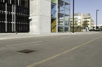 an empty street near tall buildings and a large puddle with a water spout in the middle of it