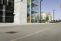 an empty street near tall buildings and a large puddle with a water spout in the middle of it