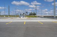 empty parking lot next to road with yellow lines painted on it and traffic lights in sky