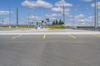 empty parking lot next to road with yellow lines painted on it and traffic lights in sky