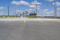 empty parking lot next to road with yellow lines painted on it and traffic lights in sky