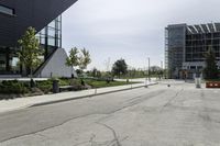 there is a very empty building and its buildings are in the background? with a bench on the side