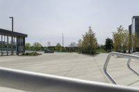 a large plaza with metal benches and tables and trees, on the outside of a tall building