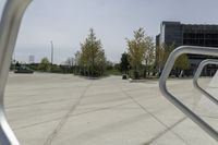 a large plaza with metal benches and tables and trees, on the outside of a tall building