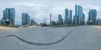 a skateboarder in motion in a skate park near city buildings with clouds overhead