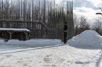 snow covered pathway outside a fence with a large pile of snow on the right side