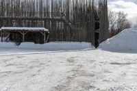 snow covered pathway outside a fence with a large pile of snow on the right side