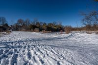 a snow covered field in the winter with shadows of a tree and a few snow on the ground