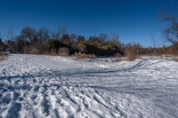 a snow covered field in the winter with shadows of a tree and a few snow on the ground