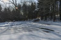 a snow covered ground with some cars in the background and some trees on the other side