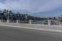 a man walking his bike along a paved walkway with marina homes and buildings on the side in the background