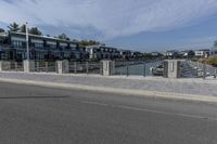 a man walking his bike along a paved walkway with marina homes and buildings on the side in the background