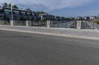 a man walking his bike along a paved walkway with marina homes and buildings on the side in the background