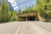 a highway under a bridge that is wide enough for a car to pass by in the mountains