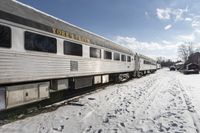 there is snow on the ground next to a passenger train car with it's windows open