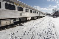 there is snow on the ground next to a passenger train car with it's windows open