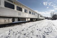 there is snow on the ground next to a passenger train car with it's windows open