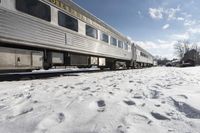 there is snow on the ground next to a passenger train car with it's windows open