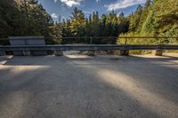 a bridge over the water in front of trees with a bench in the foreground