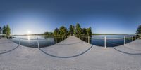 360 - ball panorama of a dock on a lake near some trees and mountains in the background