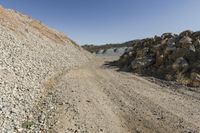 there is a bike rider on a paved dirt road through rocky area near a mountain