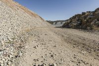 there is a bike rider on a paved dirt road through rocky area near a mountain