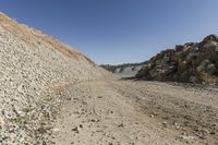 there is a bike rider on a paved dirt road through rocky area near a mountain