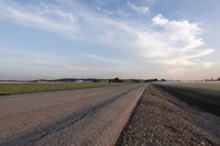 a view of a large empty road with grass on the side of the road in the background