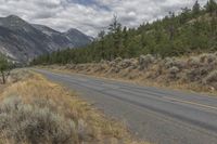 a lonely road in front of mountains and trees with no one riding it's bicycle